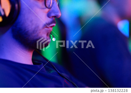 Focused Gamer With Headset and Microphone Competing in Neon Esports Tournament Environment 138132228