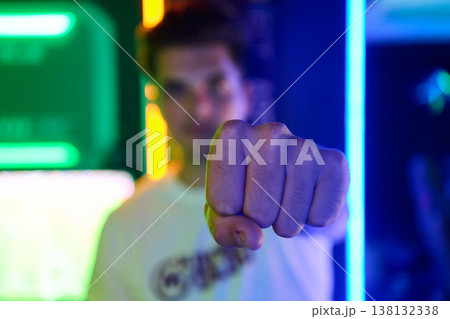 Young Man Punching Forward With Fist in Neon Lights Showing Confidence and Strength Young Man Punching Forward With Fist in Neon Lights Showing Confidence and Strength 138132338
