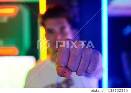 Young Man Pointing Fist Toward Camera With Neon Lights Urban Portrait Gesture Young Man Pointing Fist Toward Camera With Neon Lights Urban Portrait Gesture 138132359