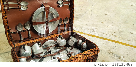 A vintage picnic suitcase with neatly arranged metal plates, cups, and cutlery. It encompasses concepts of retro lifestyle, outdoor recreation, eco-friendliness, and nostalgic travel. A vintage picnic suitcase with neatly arranged metal plates, cups, and cutlery. It encompasses concepts of retro lifestyle, outdoor recreation, eco-friendliness, and nostalgic travel. 138132468