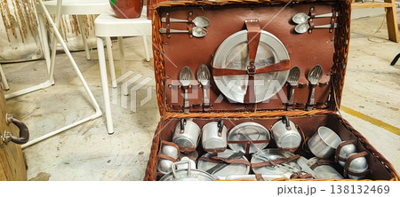 A vintage picnic suitcase with neatly arranged metal plates, cups, and cutlery. It encompasses concepts of retro lifestyle, outdoor recreation, eco-friendliness, and nostalgic travel. A vintage picnic suitcase with neatly arranged metal plates, cups, and cutlery. It encompasses concepts of retro lifestyle, outdoor recreation, eco-friendliness, and nostalgic travel. 138132469