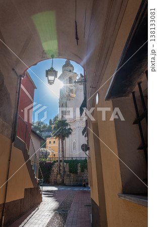 Laigueglia, liguria, italy, showing the historic san matteo parish church bell tower and sunburst through a traditional village archway leading to a sunlit town square and alley Laigueglia, liguria, italy, showing the historic san matteo parish church bell tower and sunburst through a traditional village archway leading to a sunlit town square and alley 138133081