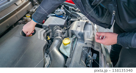 A man is checking the fuel oil level in a car. Caring for the internal combustion engine. High quality photo 138135340