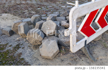 Road paving slabs piled up and cordoned off with warning signs. Road construction and repair in urban conditions. High quality photo Road paving slabs piled up and cordoned off with warning signs. Road construction and repair in urban conditions. High quality photo 138135341