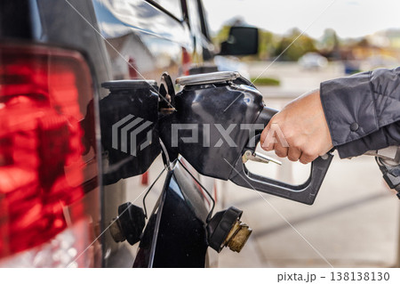 Fueling car at gas station with closeup of hand holding nozzle during gasoline shortage and energy crisis Fueling car at gas station with closeup of hand holding nozzle during gasoline shortage and energy crisis 138138130