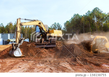 Heavy machinery works on construction site, moving soil clearing tree stumps in forest area. 138138755