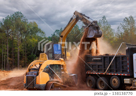 Heavy machinery digs transfers soil to dump truck at construction site at ground leveling Heavy machinery digs transfers soil to dump truck at construction site at ground leveling 138138770