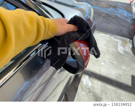 Man wiping and drying car with grey microfiber rag outdoors, closeup Man wiping and drying car with grey microfiber rag outdoors, closeup 138139052