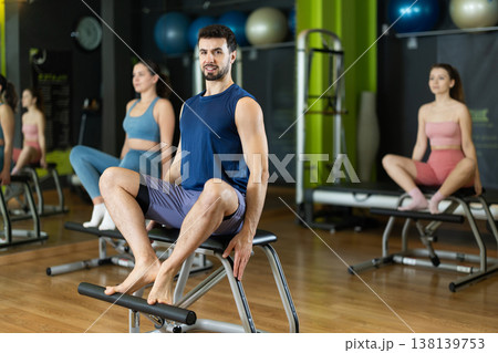 Young man doing leg presses on pilates chair Young man doing leg presses on pilates chair 138139753