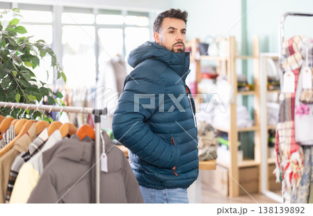 Man choosing a jacket of his size in a clothing store Man choosing a jacket of his size in a clothing store 138139892
