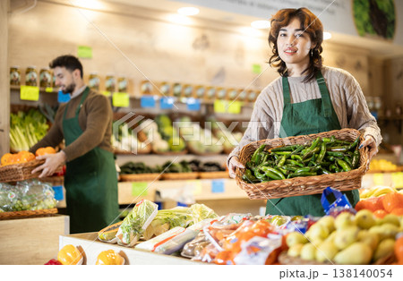 Young woman seller with box of green peppers 138140054