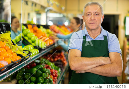 Portrait of skilled male seller in uniform looking at camera during work day in grocery supermarket Portrait of skilled male seller in uniform looking at camera during work day in grocery supermarket 138140056