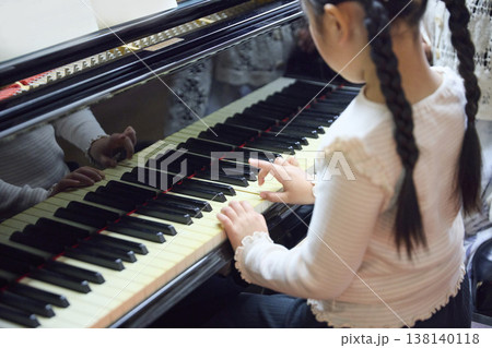 ピアノを練習する女の子の手元を見守る女性講師 ピアノを練習する女の子の手元を見守る女性講師 138140118