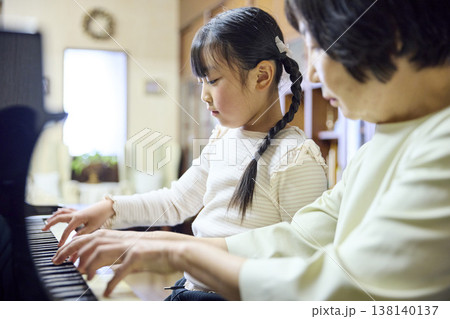 シニア講師と並んでピアノを弾く小学生の女の子 シニア講師と並んでピアノを弾く小学生の女の子 138140137