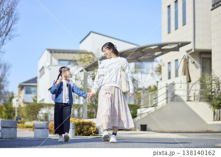 住宅街を手を繋いで歩く母親とランドセルを背負った女の子 住宅街を手を繋いで歩く母親とランドセルを背負った女の子 138140162