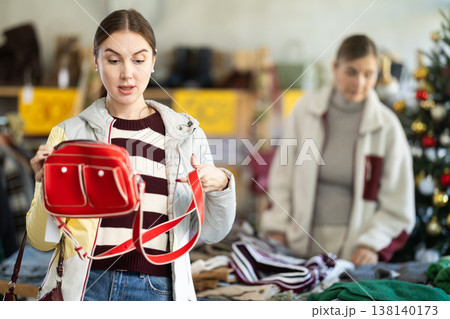 Woman client looks at products in store, choose closely ladys bag 138140173