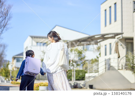 住宅街で娘を見守りながら手をつないで歩く母親 住宅街で娘を見守りながら手をつないで歩く母親 138140176