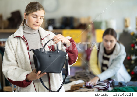 Woman client looks at products in store, choose closely ladys bag Woman client looks at products in store, choose closely ladys bag 138140221