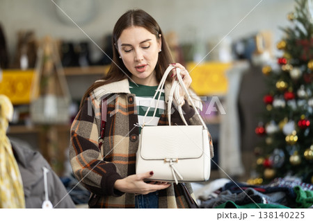 adult woman chooses fashionable handbags in a store against the background of a Christmas tree 138140225