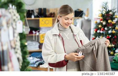 Adult woman choosing trousers in clothing store 138140387