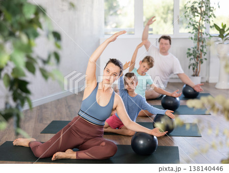 Calm middle-aged woman sitting in half lotus pose putting one hand on softball 138140446