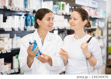 In cosmetic department of pharmacy, buyer asks consultant to help and choose cleansing gel. 138140470