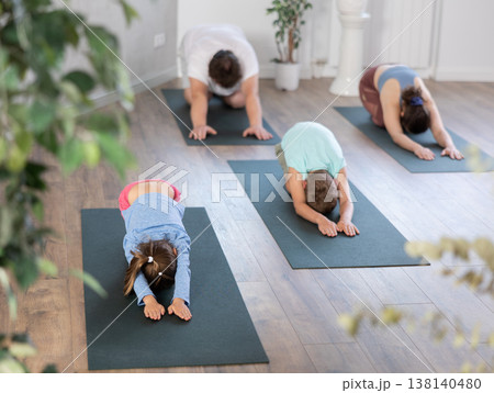 Family yoga, parents with son and daughter sitting in pose of child, restoring Balasana for rest Family yoga, parents with son and daughter sitting in pose of child, restoring Balasana for rest 138140480