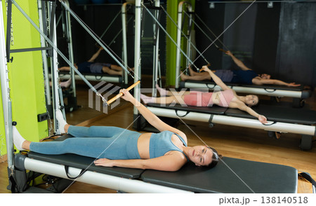 Woman lying on reformer in Pilates Woman lying on reformer in Pilates 138140518