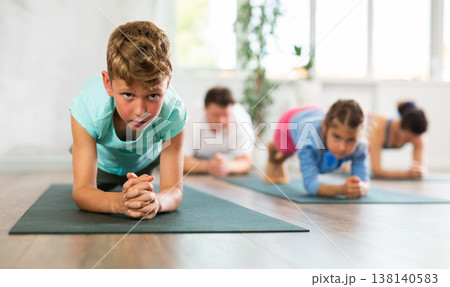 Little boy with his family practicing yoga in studio Little boy with his family practicing yoga in studio 138140583