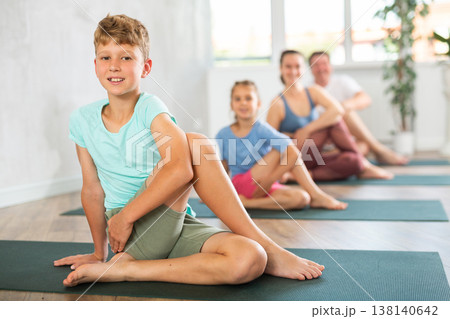 Parents together with children practice yoga in Gomukhasana pose in gym 138140642