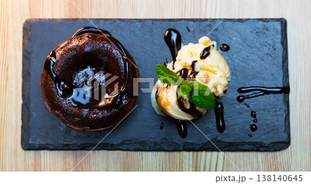 Sweet lava cake served with vanilla ice cream and mint at black plate Sweet lava cake served with vanilla ice cream and mint at black plate 138140645