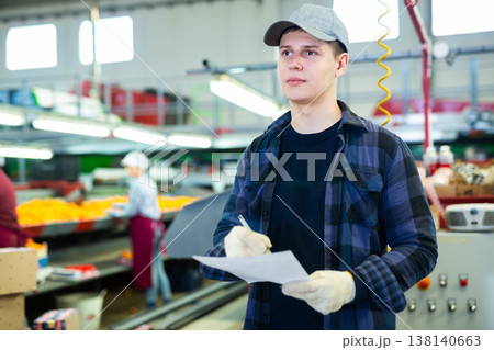 Young supervisor inspecting workflow of citrus sorting workshop 138140663