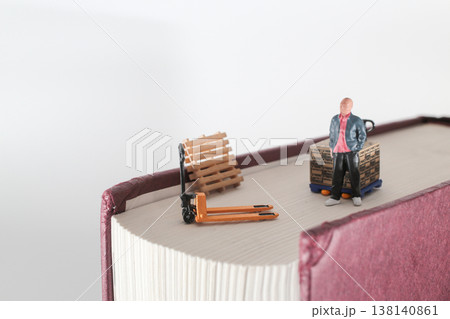 Miniature Worker Stands Beside Pallet and Hand Truck 138140861