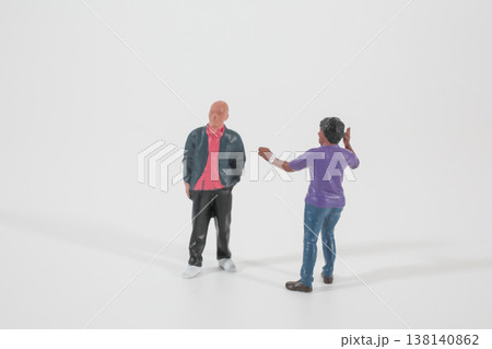 Miniature Figures Engaged in Conversation on Clean Studio Surface 138140862