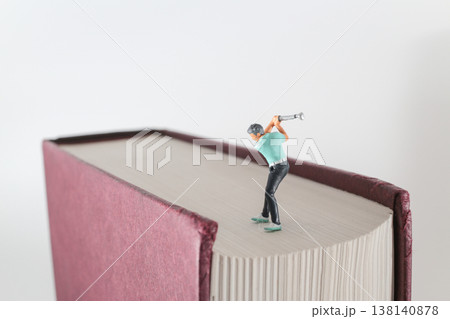 Miniature Golfer Finishes Swing On Oversized Book Surface Miniature Golfer Finishes Swing On Oversized Book Surface 138140878