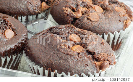 Freshly baked chocolate muffins stacked surface with chocolate chunks beside them 138142087