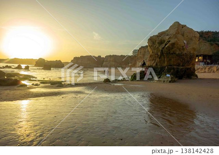 Golden hour idyllic vacation beach scene Algarve Portugal Praia do Amado big sun 138142428
