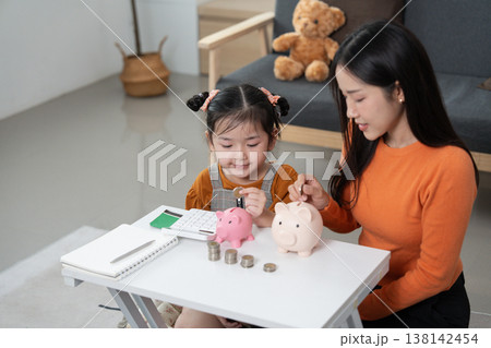 Mother and daughter learning savings with piggy banks Mother and daughter learning savings with piggy banks 138142454