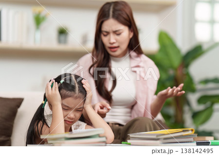 Mother assisting daughter with schoolwork at home Mother assisting daughter with schoolwork at home 138142495