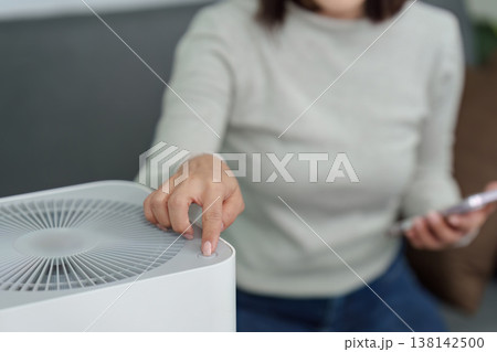 Close-up of hand operating air purifier control panel Close-up of hand operating air purifier control panel 138142500