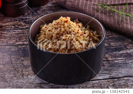 Healthy cooked tri-color quinoa in a bowl with fresh tomatoes and rosemary on a rustic wooden table Healthy cooked tri-color quinoa in a bowl with fresh tomatoes and rosemary on a rustic wooden table 138142541