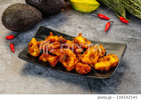 Crispy fried calamari rings appetizer on a plate with fresh chili and avocado. 138142545