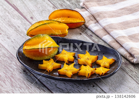 Fresh sliced star fruit and whole carambola on a plate over a rustic wooden background. Fresh sliced star fruit and whole carambola on a plate over a rustic wooden background. 138142606