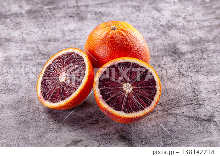 Fresh whole and sliced blood oranges on a grey textured background. 138142718