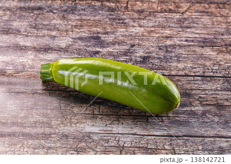 Fresh single green zucchini on a rustic wooden table background Fresh single green zucchini on a rustic wooden table background 138142721