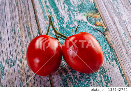 Ripe red tomatoes on a vine resting on a rustic painted wood background. Ripe red tomatoes on a vine resting on a rustic painted wood background. 138142722