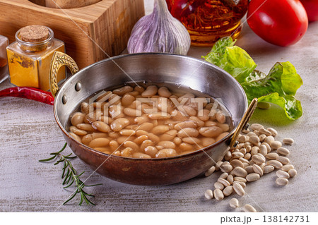 Cooked white beans in a rustic metal bowl surrounded by fresh ingredients for a healthy meal. Cooked white beans in a rustic metal bowl surrounded by fresh ingredients for a healthy meal. 138142731