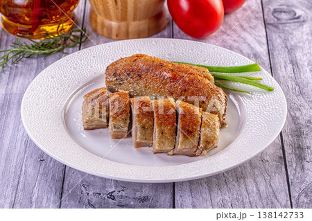 Gourmet roasted duck breast sliced on a white plate, served with green onions on a rustic table. Gourmet roasted duck breast sliced on a white plate, served with green onions on a rustic table. 138142733
