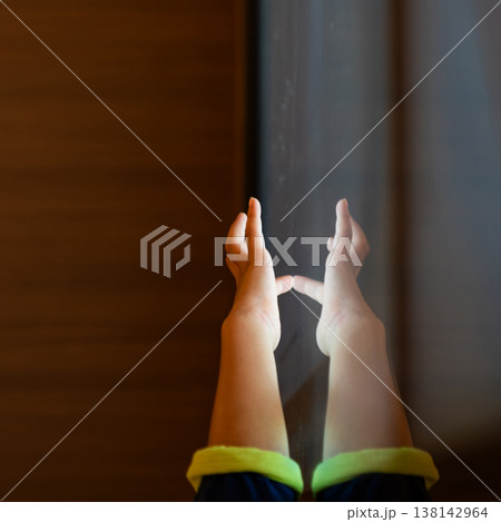 Child hand touching an illuminated interactive surface with reflection representing human connection with technology and digital interaction. Child hand touching an illuminated interactive surface with reflection representing human connection with technology and digital interaction. 138142964
