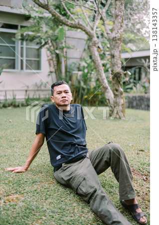 Portrait of Relaxed Asian Man Sitting on Grass Outdoors 138143357